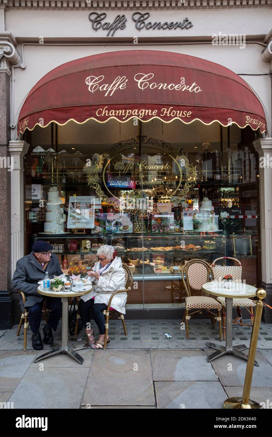 Una coppia anziana gusterà il tè pomeridiano mentre si siede all'esterno del caffe Concerto su Shaftesbury Avenue, cuore del West End di Londra, Inghilterra, Regno Unito Foto Stock