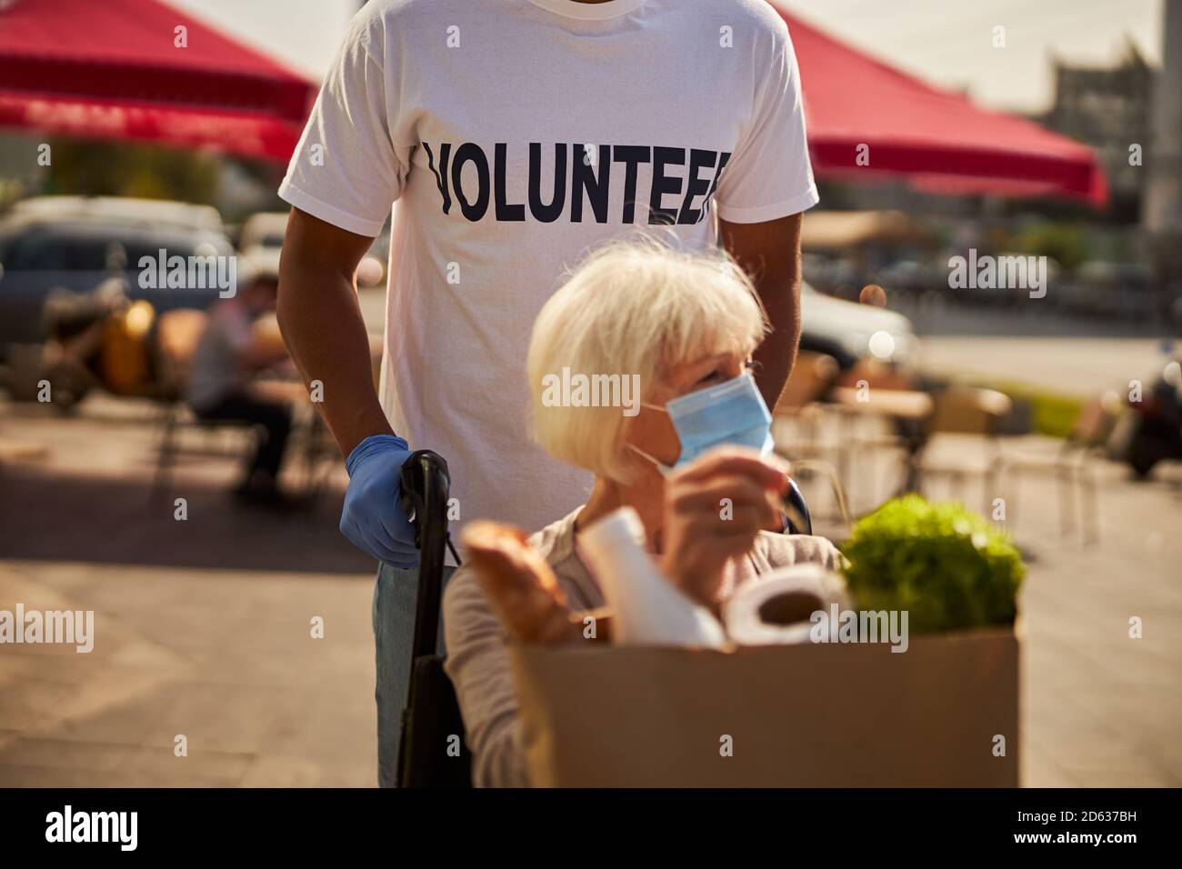 Donna anziana di ritorno volontaria maschile dal supermercato Foto Stock