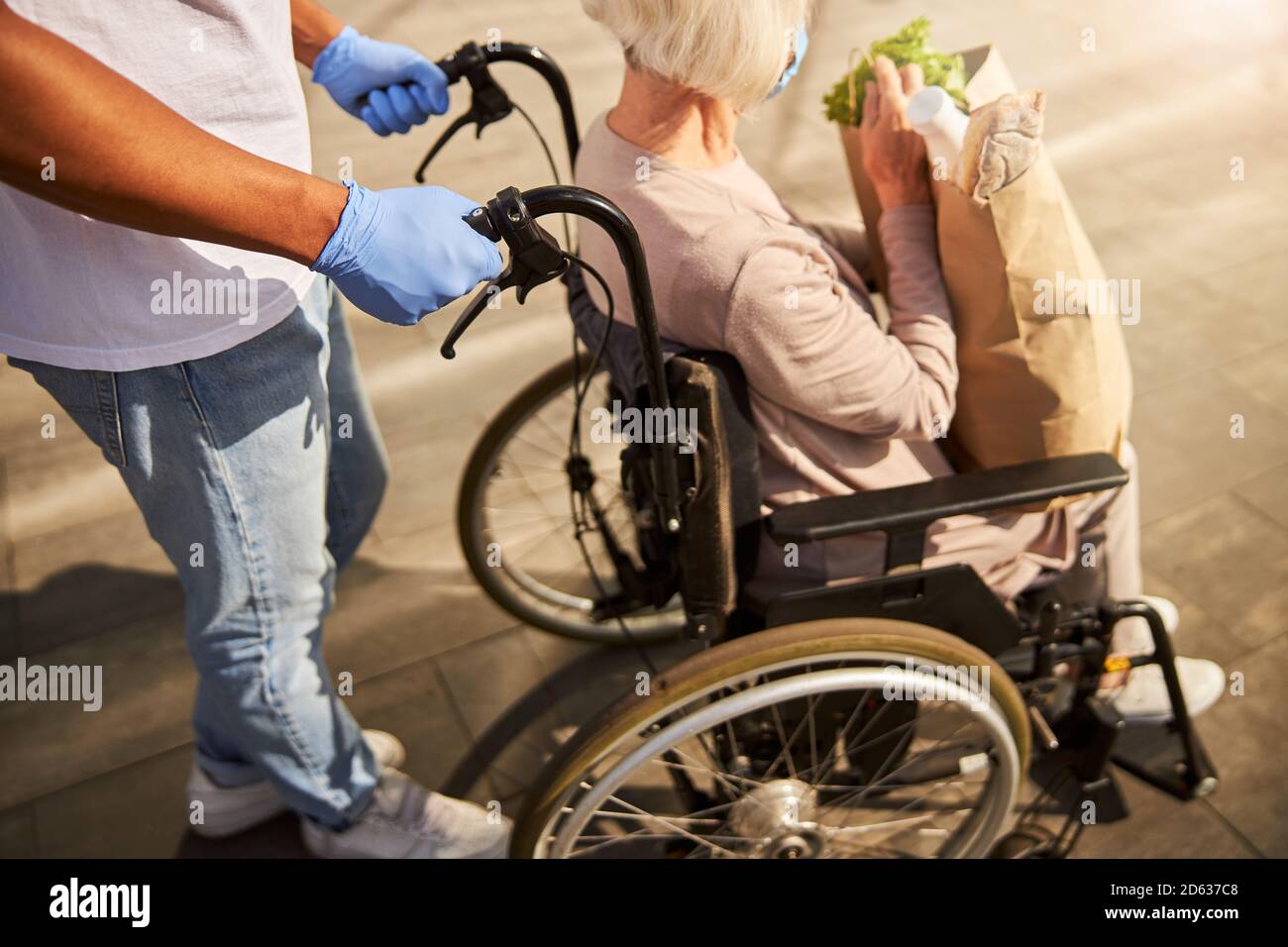 Donna dai capelli grigi seduta comodamente su una sedia a rotelle nera Foto Stock