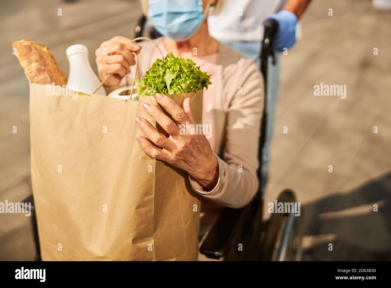 Donna in pensione che trasporta un sacchetto di carta del deposito della drogheria con il cibo Foto Stock