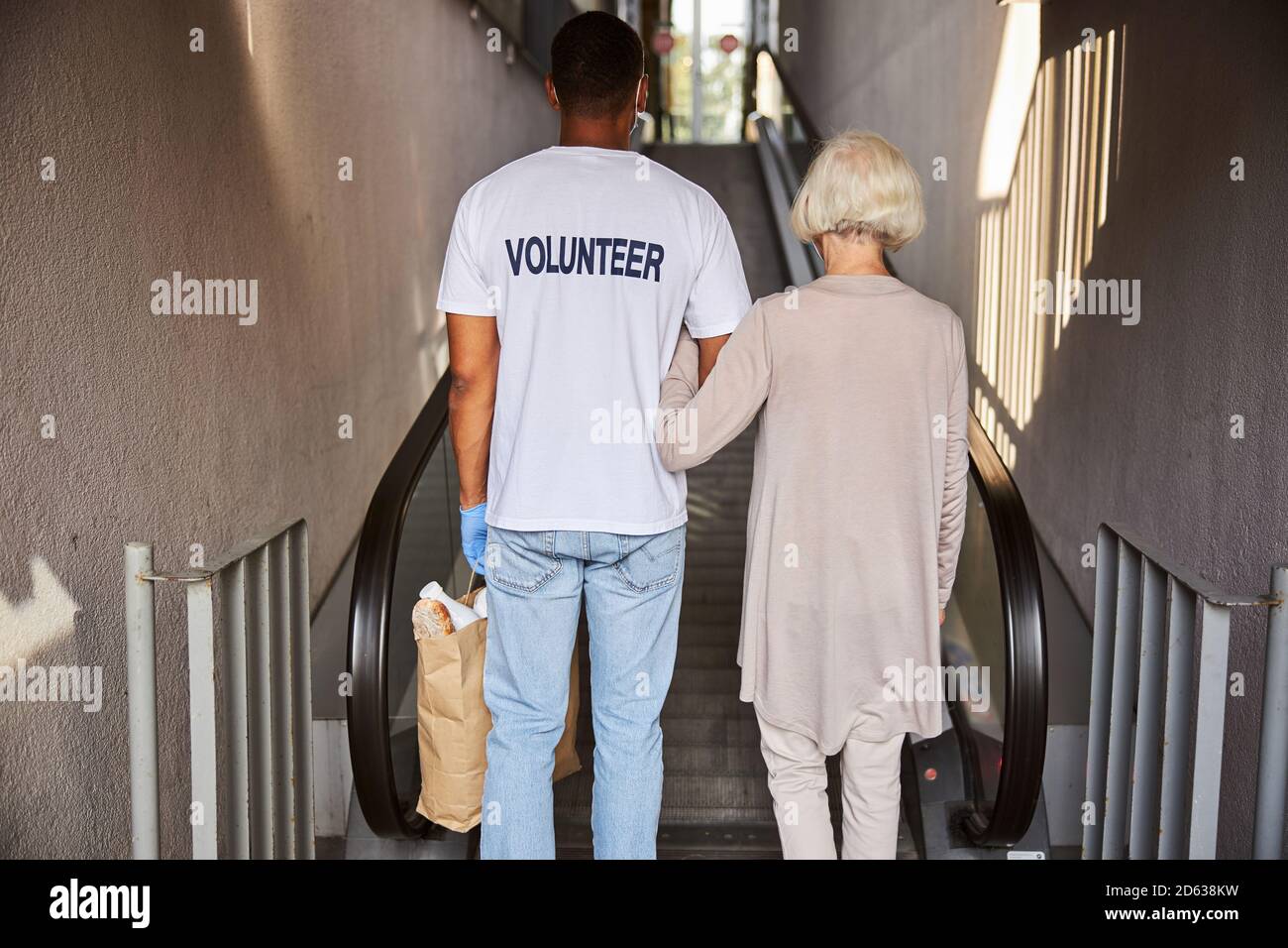 Donna anziana e il suo assistente che entrano in un centro commerciale Foto Stock