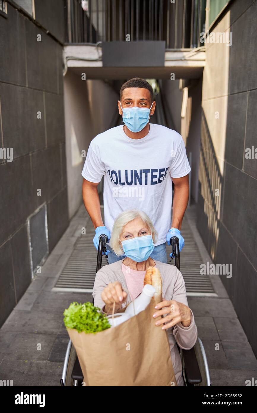 Donna felice anziana e volontaria in partenza da un centro commerciale Foto Stock