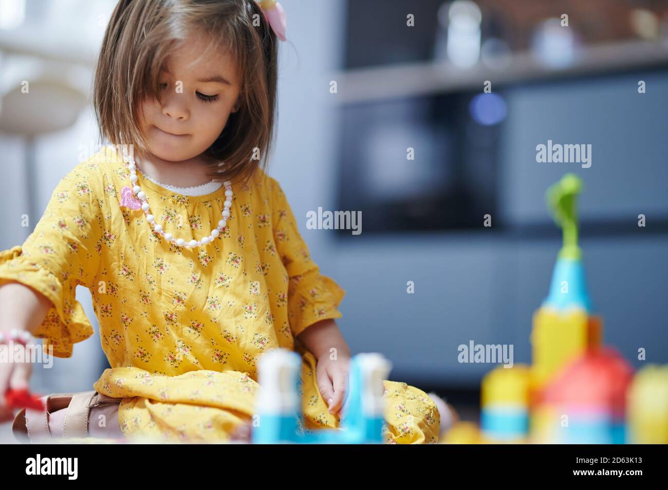 Una ragazza gioca con mattoni colorati sullo sfondo della casa con spazio per la copia Foto Stock