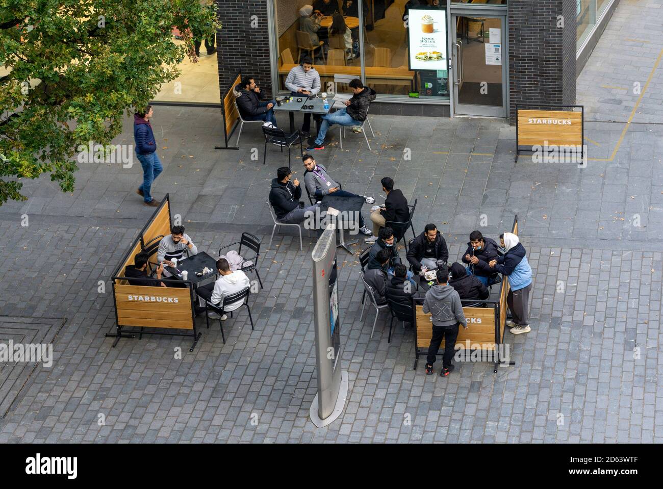 I giovani gruppi di uomini e donne del Medio Oriente si riuniscono a. Uno Starbucks nel centro di Liverpool Foto Stock