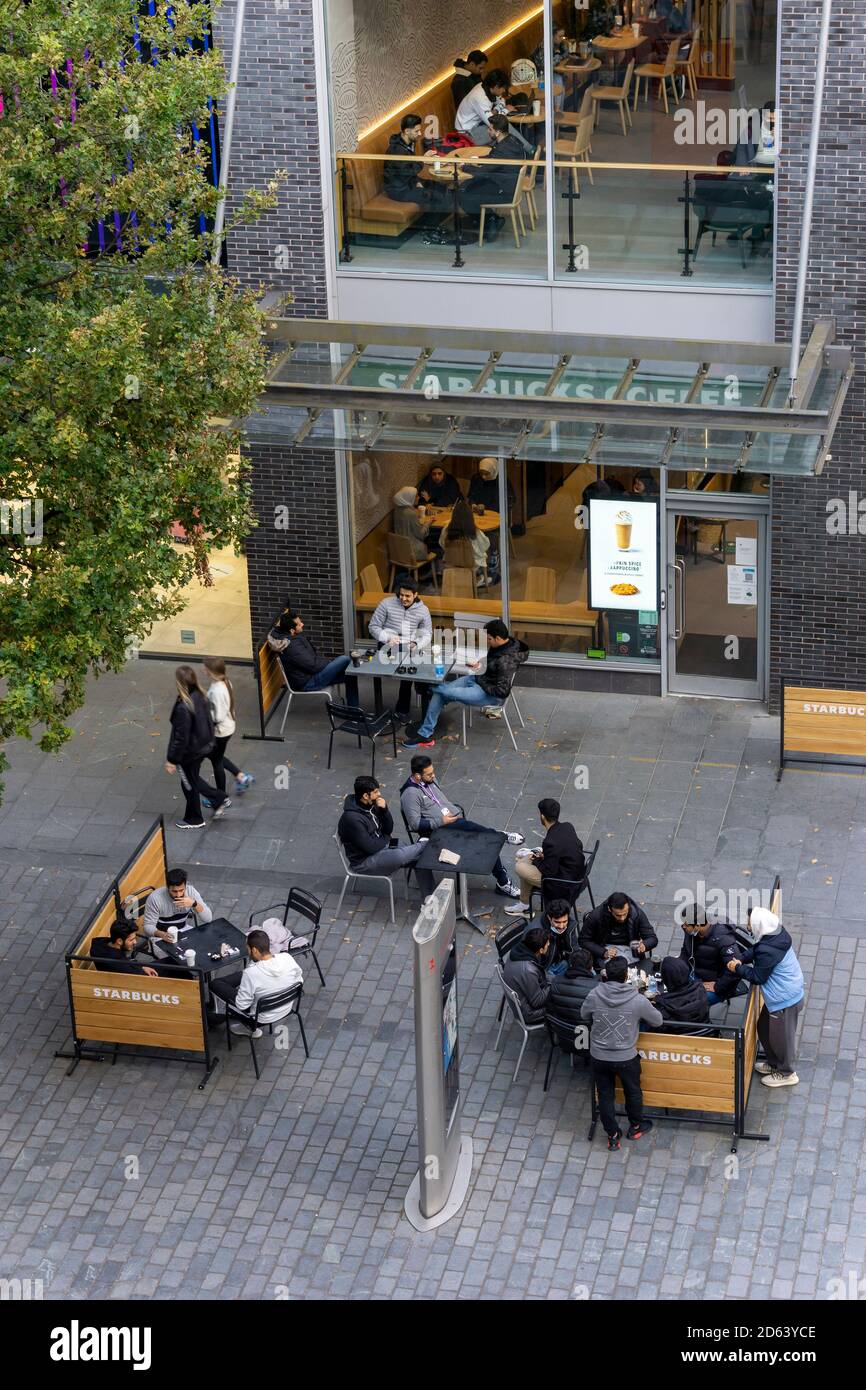 I giovani gruppi di uomini e donne del Medio Oriente si riuniscono a. Uno Starbucks nel centro di Liverpool Foto Stock