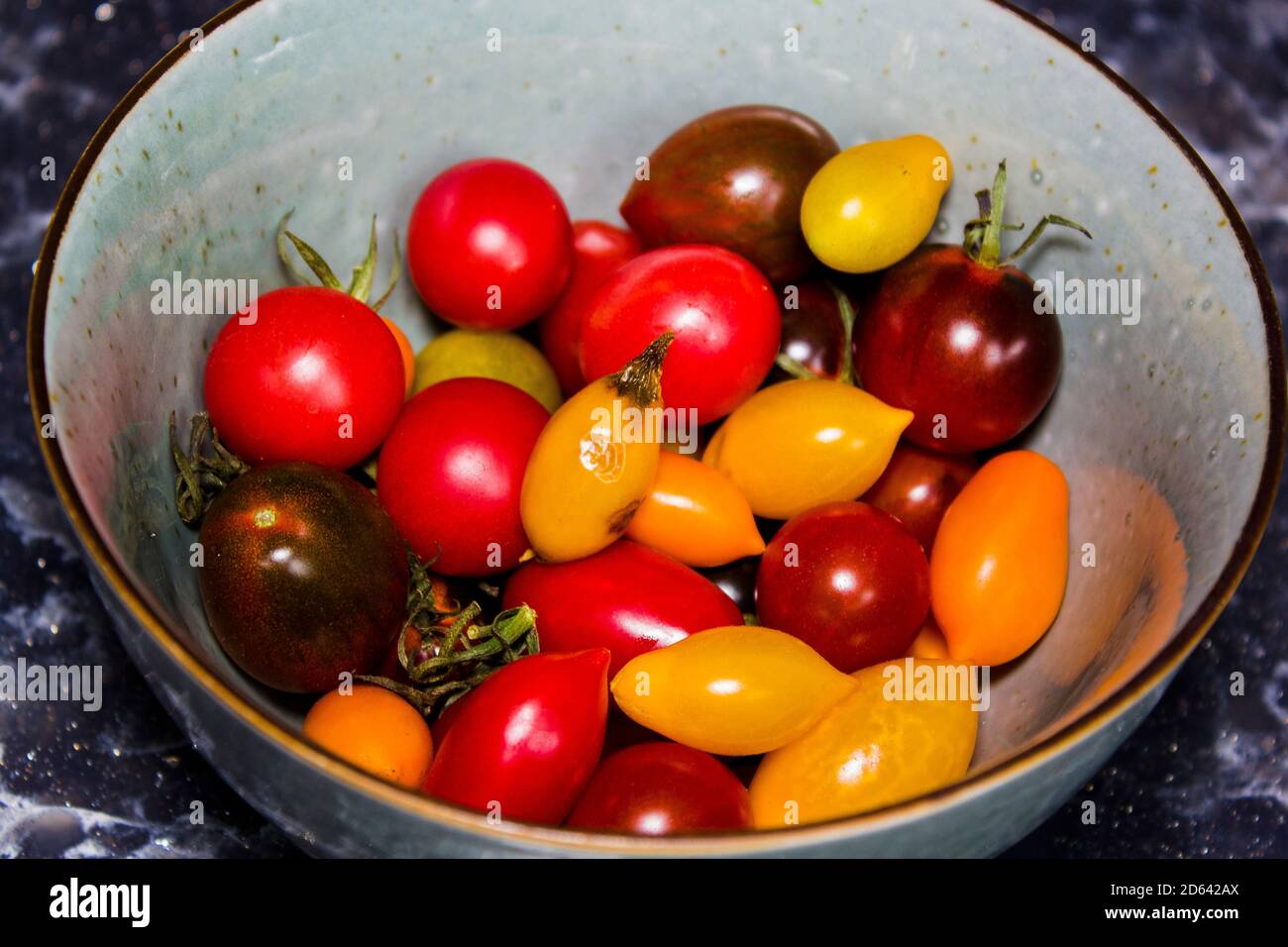 Mini pomodori rossi gialli e arancioni in una ciotola Foto Stock