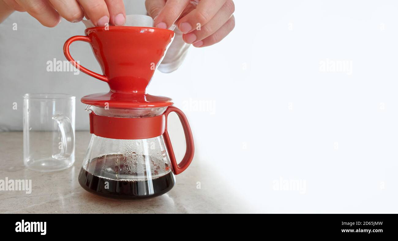 L'uomo eroga a casa v 60. Mette il filtro di carta in un gocciolatore di  ceramica e versa acqua calda, preparando il filtro per versare il caffè  Foto stock - Alamy