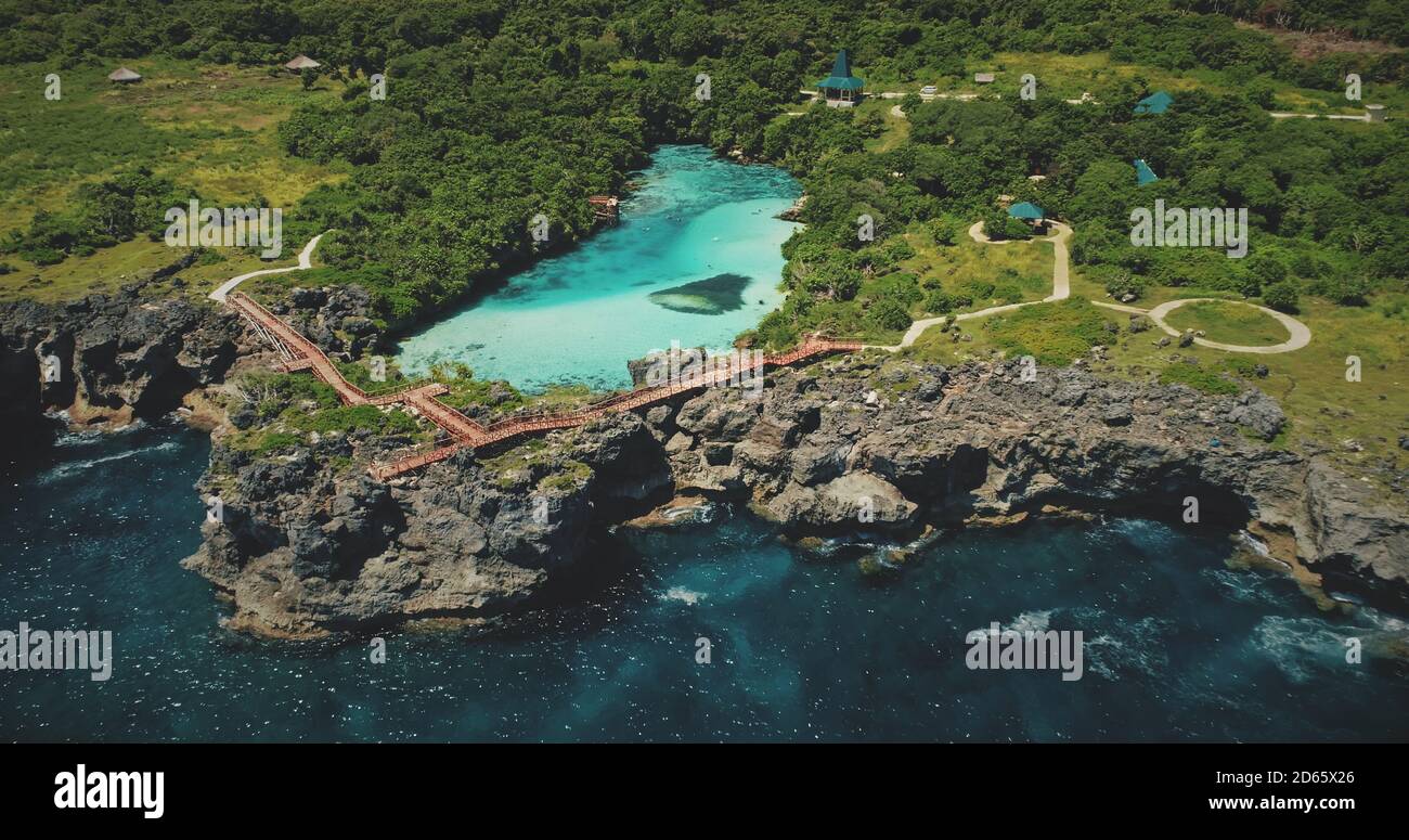 Scogliera mare costa con paesaggio verde con lago limpido in cima in vista aerea. Scenico paesaggio marino admist natura tropicale verde a Weekuri laguna, Sumba Island, Indonesia. Scatto con drone cinematografico Foto Stock