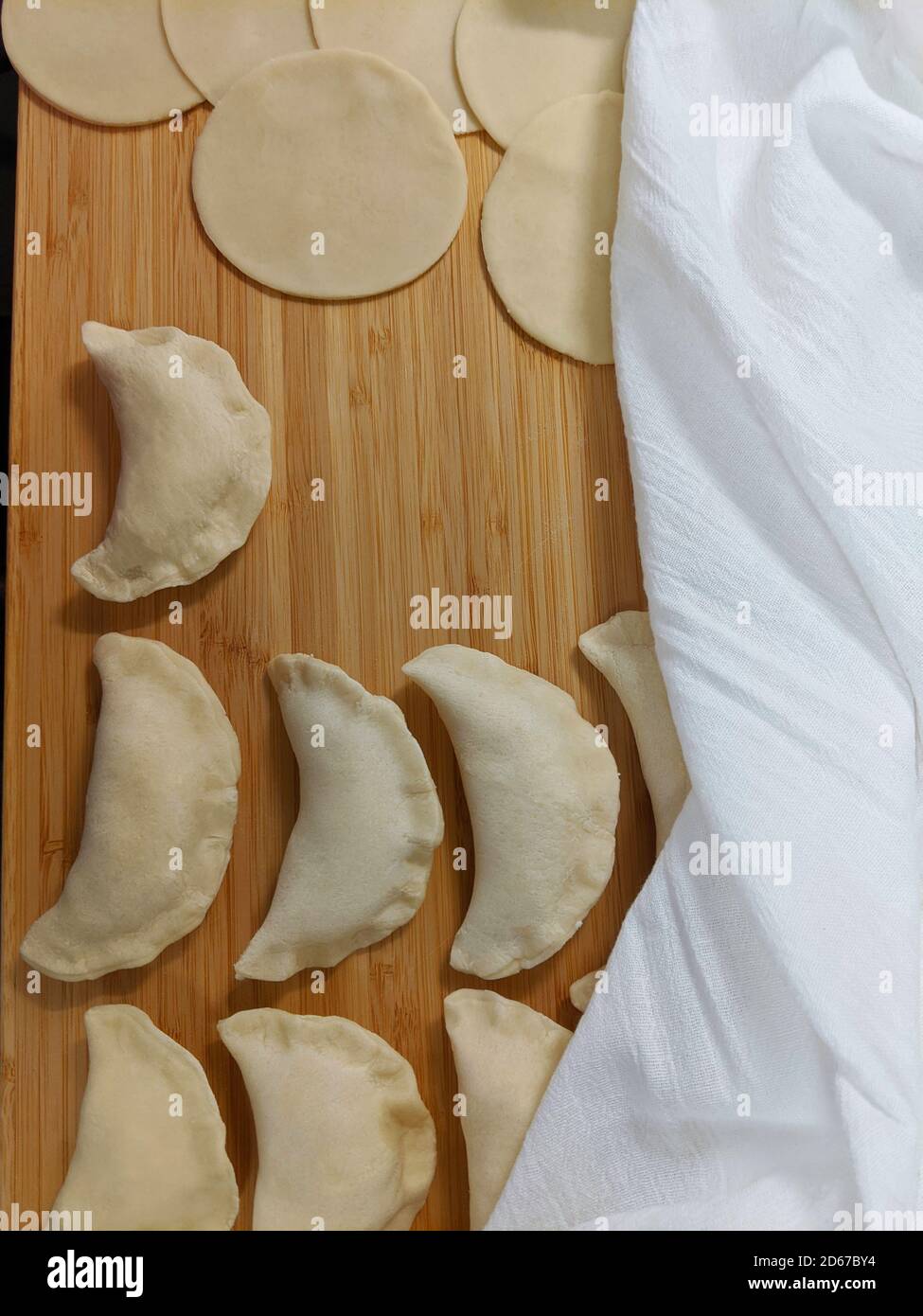 Pierogis e pasta su tavola di legno, parzialmente ricoperta di tela di cotone bianca Foto Stock