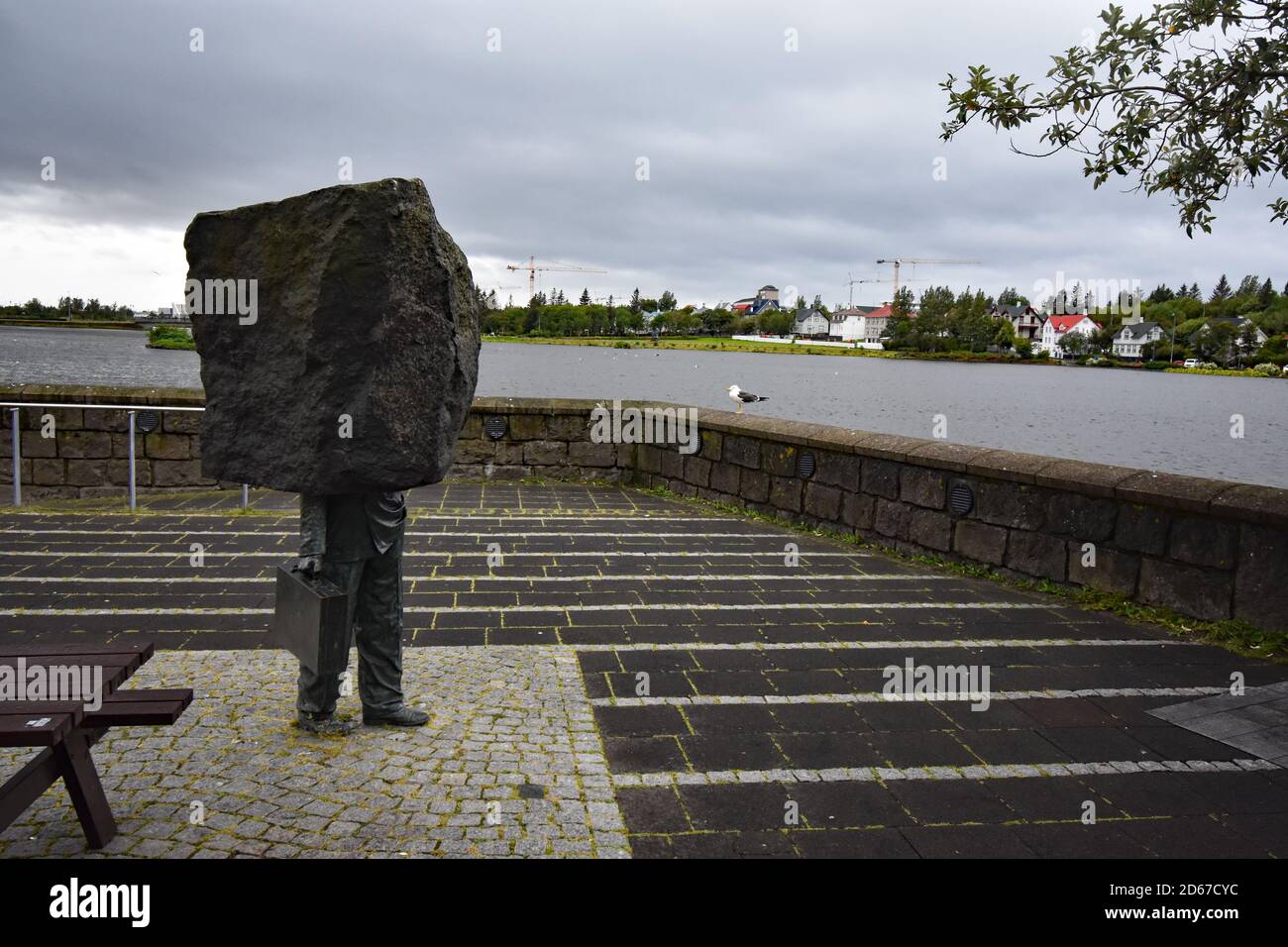 Monumento al burocrate sconosciuto sul bordo del lago Tjornin, Reykjavik, Islanda. Una scultura raffigurante la metà inferiore di un uomo che porta una valigetta. Foto Stock