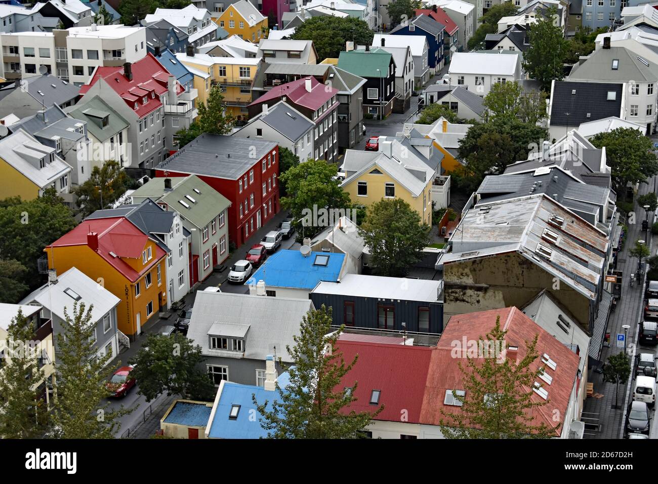 Una vista dalla cima della torre della chiesa di Hallgrimskirkja. File di case dai colori vivaci e auto parcheggiate possono essere viste attraverso la città di Reykjavik, Islanda. Foto Stock