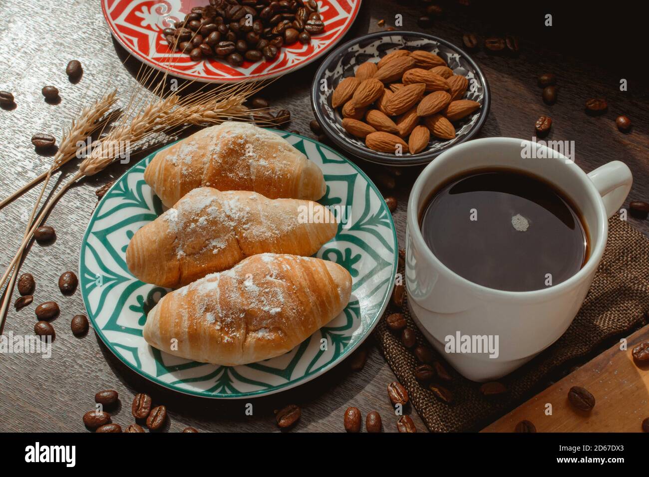 colazione con pane e caffè su tavolo di legno con caffè fagioli e mandorle sotto la luce del giorno a 45 gradi Foto Stock