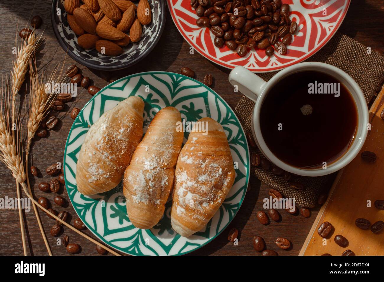colazione con pane e caffè su tavolo di legno con caffè fagioli e mandorle sotto la luce del giorno in aereo Foto Stock
