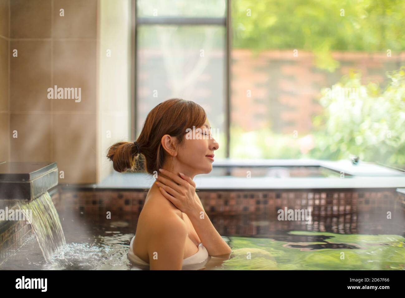 Asian giovane donna rilassante e massaggiante in primavera calda Foto Stock