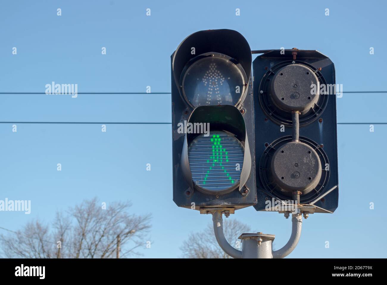 Il semaforo a due sezioni si affaccia su entrambe le direzioni, installato all'incrocio delle rotaie nella parte inferiore del quale è illuminato il simbolo della persona verde che cammina. Foto Stock