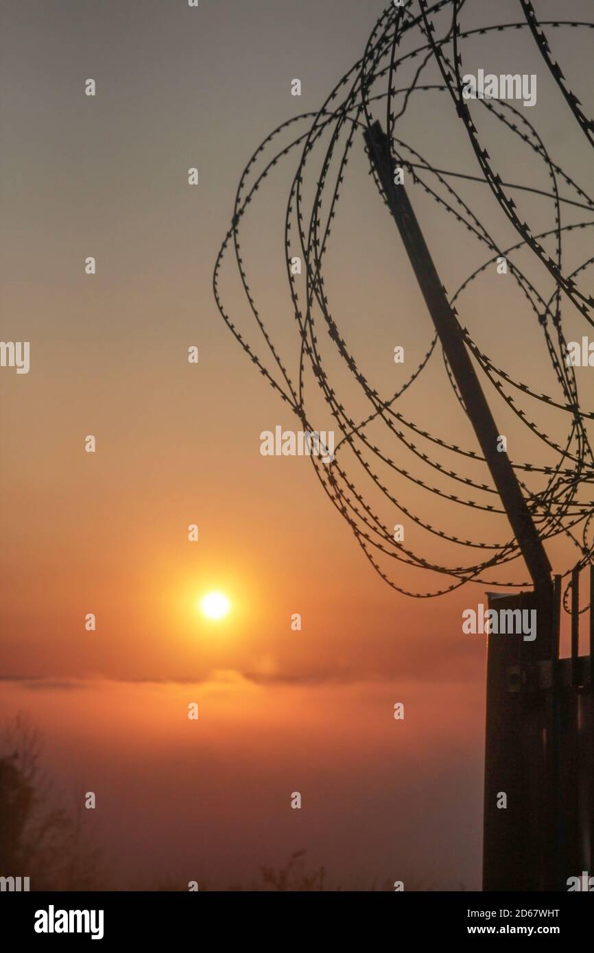 Alba su una mattina d'autunno foggy dietro un filo spinato recinzione Foto Stock