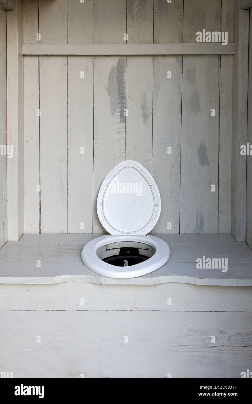 Un semplice bagno rurale pulito con una sede in plastica in una cabina di legno, vita nel villaggio. Foto Stock