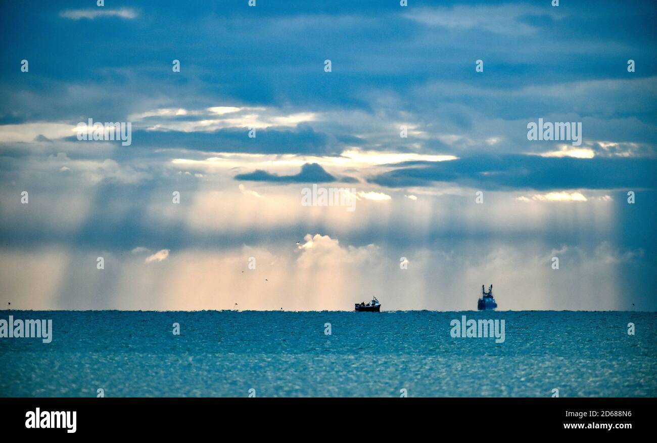 Brighton UK 15 ottobre 2020 - i pescherecci a strascico che escono dal porto di Shoreham, vicino a Brighton, sono illuminati da alberi di luce mentre le nuvole scure si raccolgono in alto . I negoziati sulla Brexit, compresi i diritti di pesca, proseguono tra il governo britannico e l'Unione europea : Credit Simon Dack / Alamy Live News Foto Stock