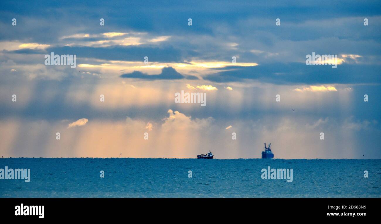 Brighton UK 15 ottobre 2020 - i pescherecci a strascico che escono dal porto di Shoreham, vicino a Brighton, sono illuminati da alberi di luce mentre le nuvole scure si raccolgono in alto . I negoziati sulla Brexit, compresi i diritti di pesca, proseguono tra il governo britannico e l'Unione europea : Credit Simon Dack / Alamy Live News Foto Stock