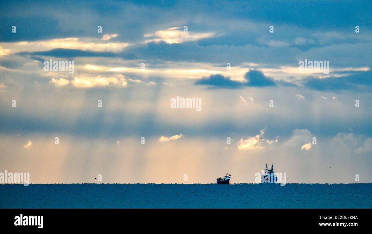Brighton UK 15 ottobre 2020 - i pescherecci a strascico che escono dal porto di Shoreham, vicino a Brighton, sono illuminati da alberi di luce mentre le nuvole scure si raccolgono in alto . I negoziati sulla Brexit, compresi i diritti di pesca, proseguono tra il governo britannico e l'Unione europea : Credit Simon Dack / Alamy Live News Foto Stock