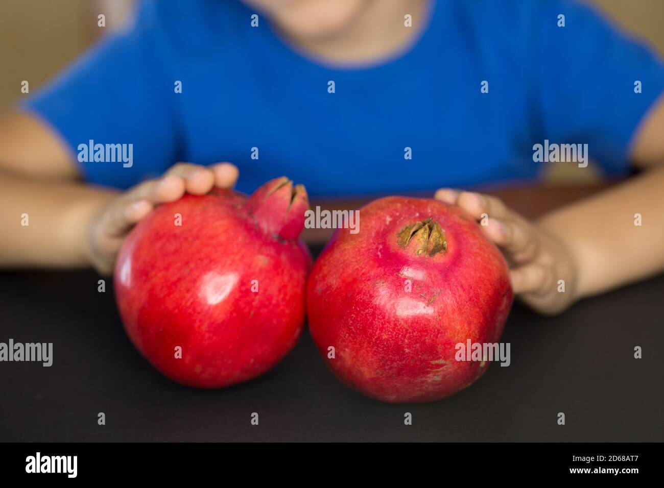 Bambino che tiene due melograni rossi Foto Stock
