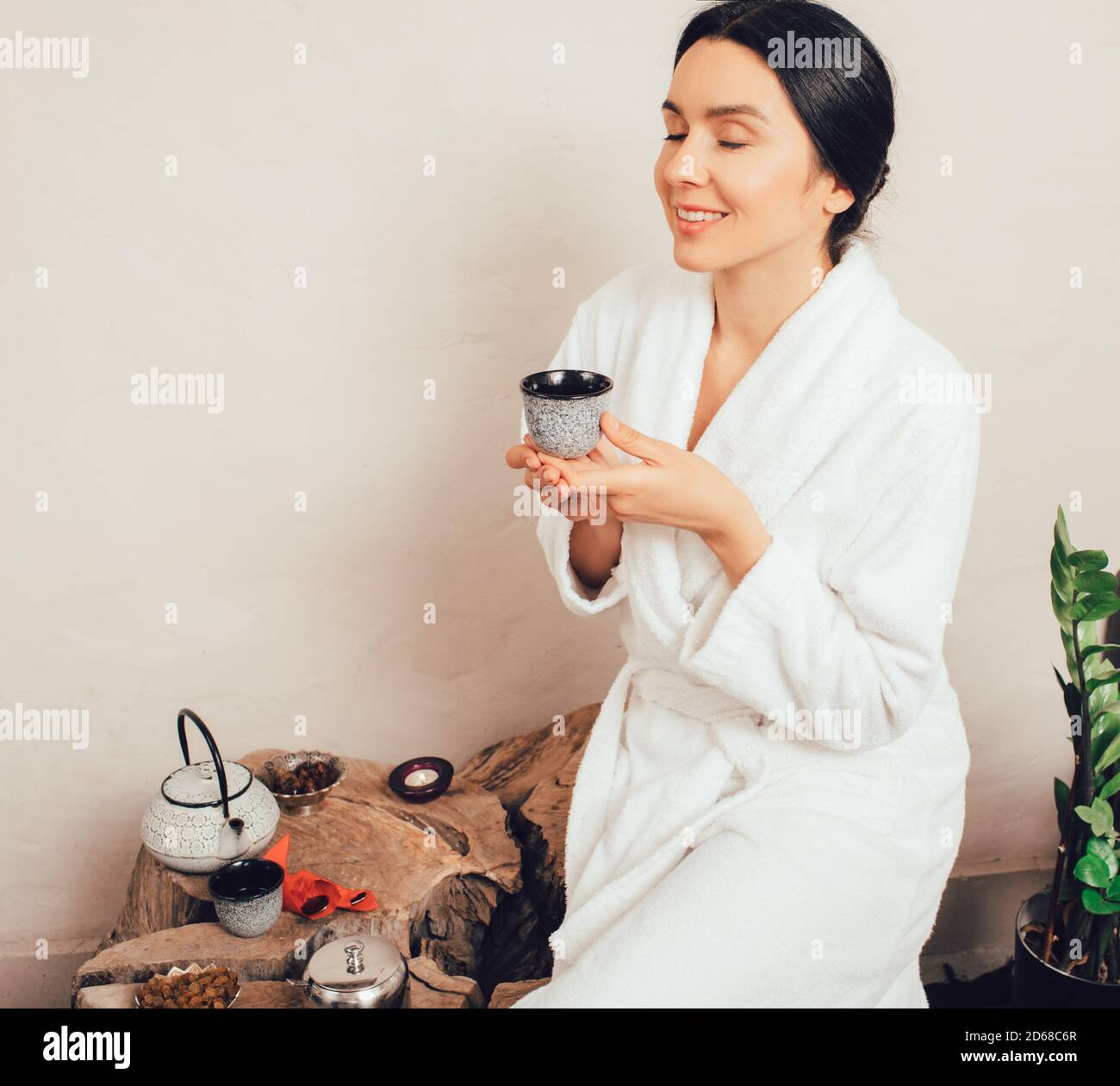 Ritratto di donna caucasica in accappatoio, tenendo in mano una tazza da tè, sorridente riposo nel centro termale. Foto Stock