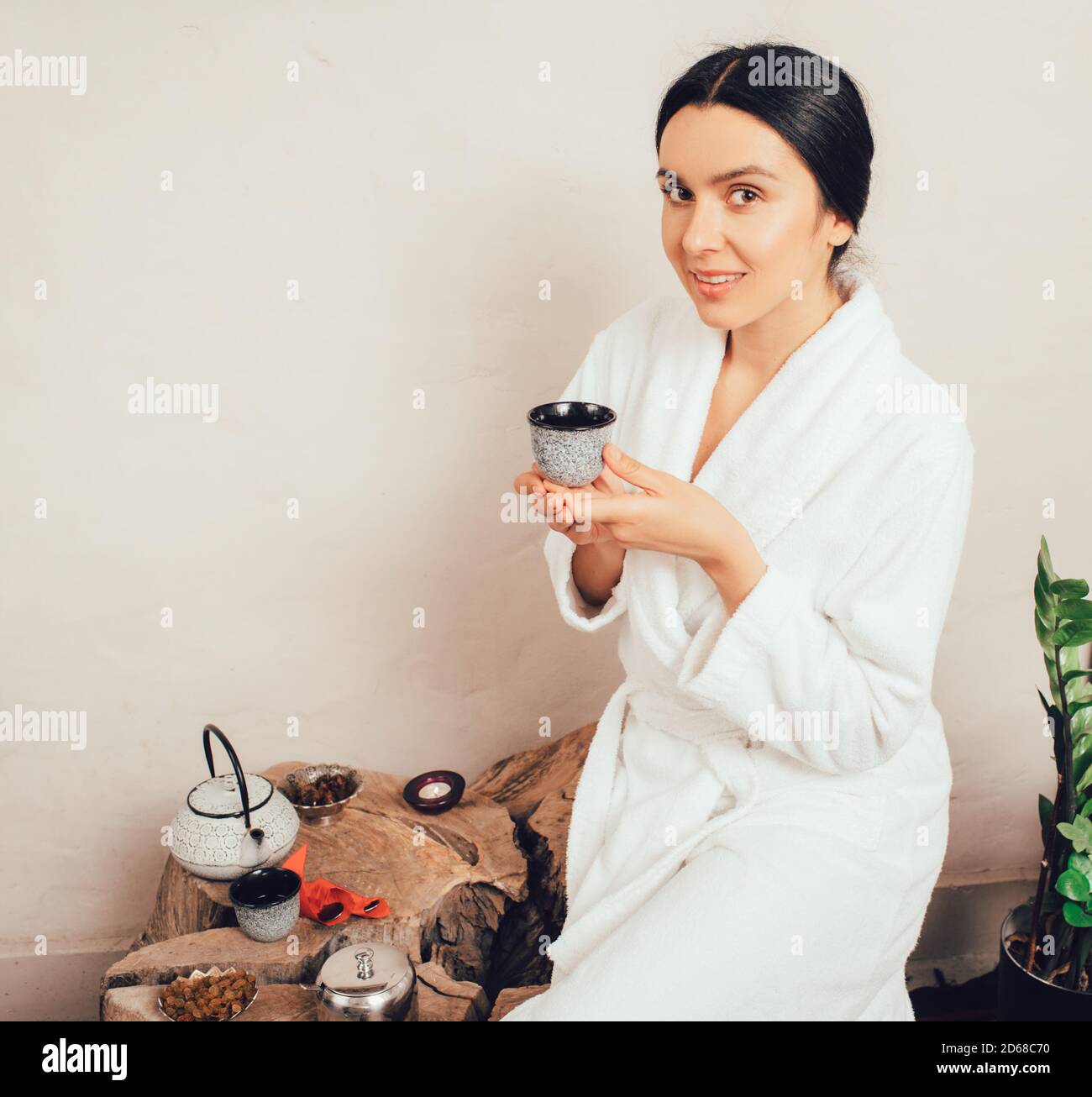 Ritratto di una sana donna di 35 anni in accappatoio che beve il tè e godendo di una giornata termale Foto Stock