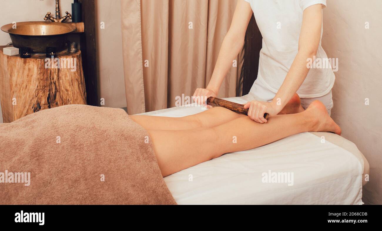 Donna che ottiene il massaggio dei piedi terapista femminile con bastoni di bambù. Benessere presso il centro benessere. Massaggio linfodrenante Foto Stock