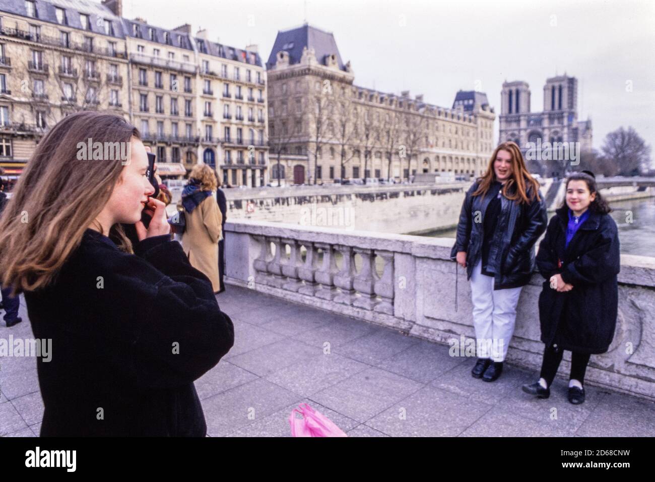 Una ragazza scatta una fotografia di due amici su un ponte sulla Senna. Studenti di una scuola del convento di Newham a Londra in una visita educativa a Parigi. 26 gennaio 1993. Foto: Neil Turner Foto Stock