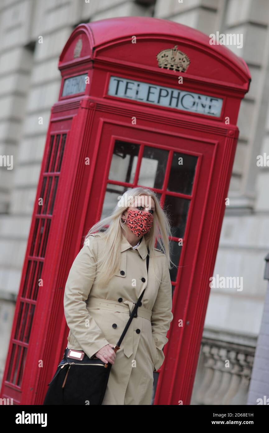 Una donna in maschera a Londra, dopo che il primo ministro Boris Johnson ha stabilito un nuovo sistema a tre livelli di allarme per l'Inghilterra a seguito di crescenti casi di coronavirus e ricoveri ospedalieri. Foto Stock