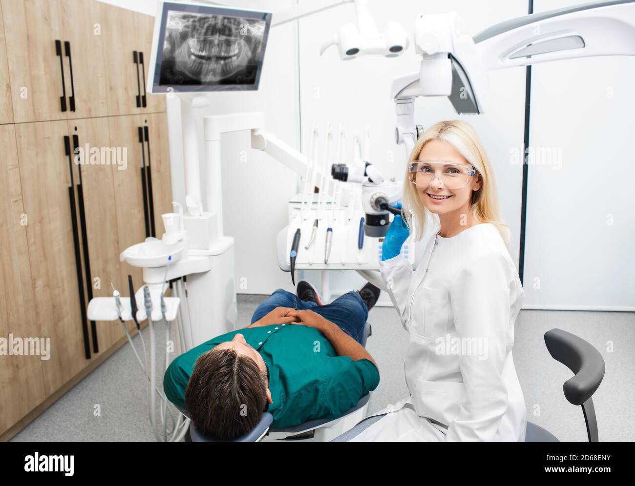 Ritratto di una bella dentista femminile in uniforme medica mentre trattamento di un paziente in uno studio odontoiatrico Foto Stock