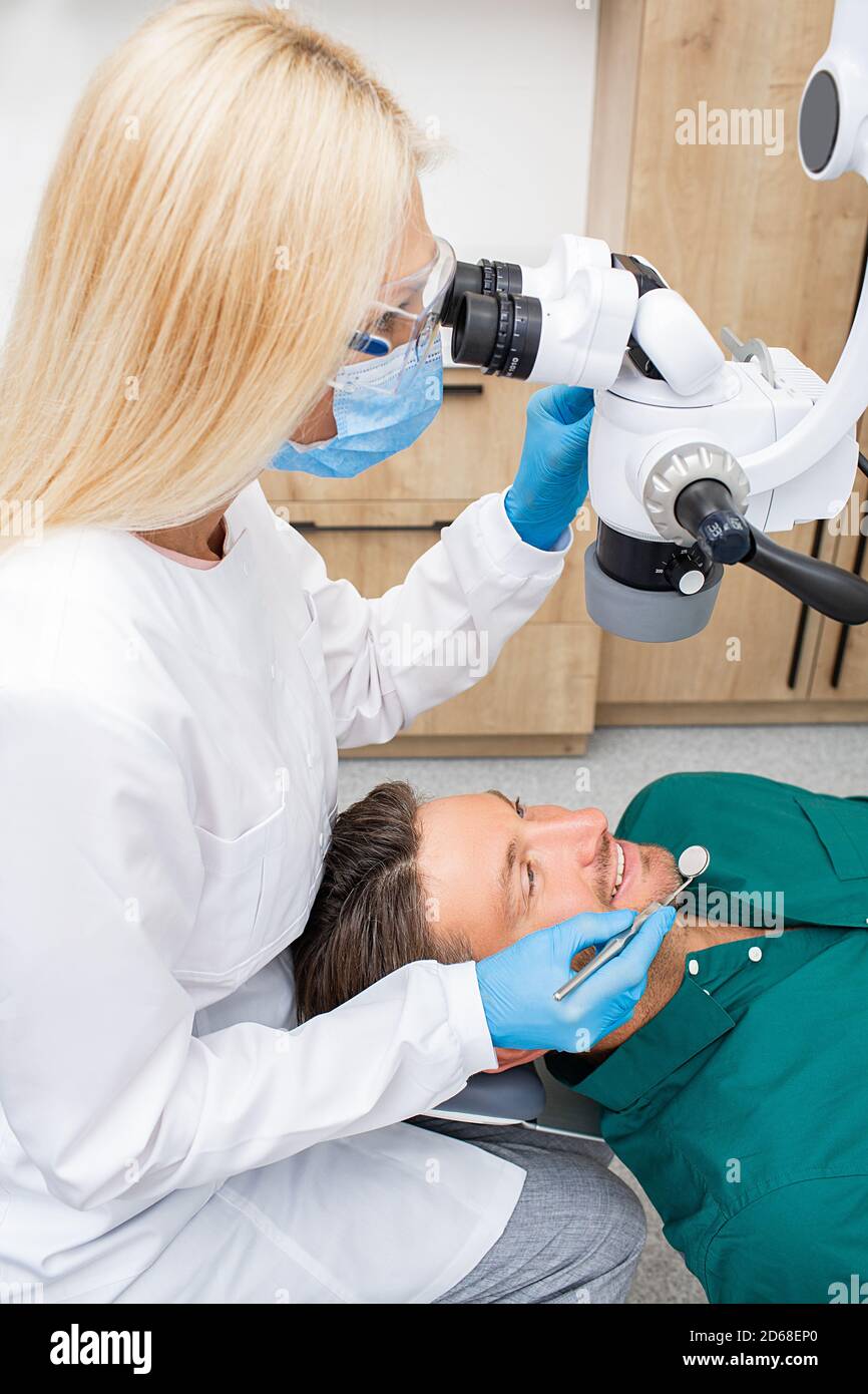 Dentista durante il lavoro. Trattamento dei denti ad un paziente utilizzando un microscopio presso la clinica odontoiatrica. Moderna tecnologia stomatologica Foto Stock