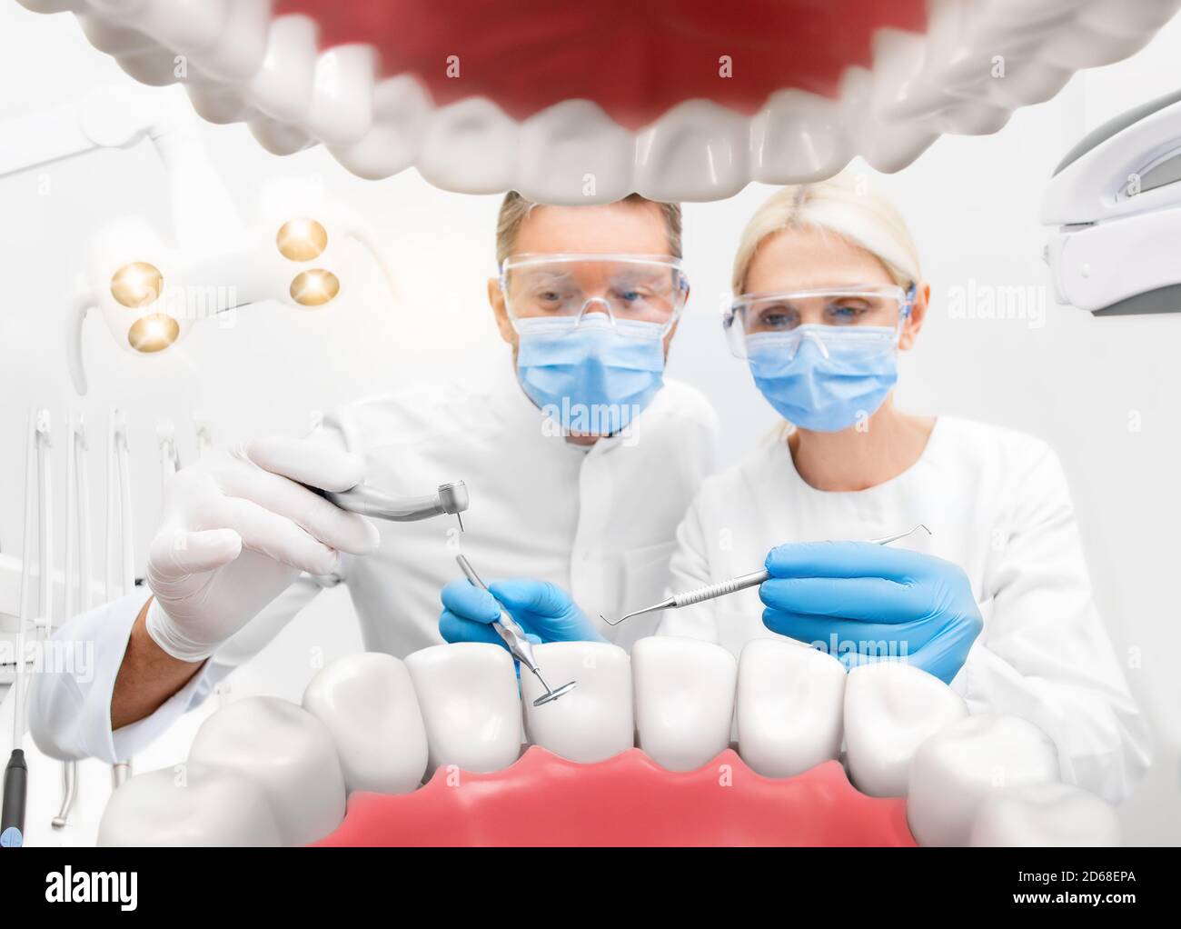 Dentista e assistente con trapano dentale e specchio dentale, trattamento dei denti, concetto creativo di odontoiatria. Vista dalla bocca aperta del paziente Foto Stock