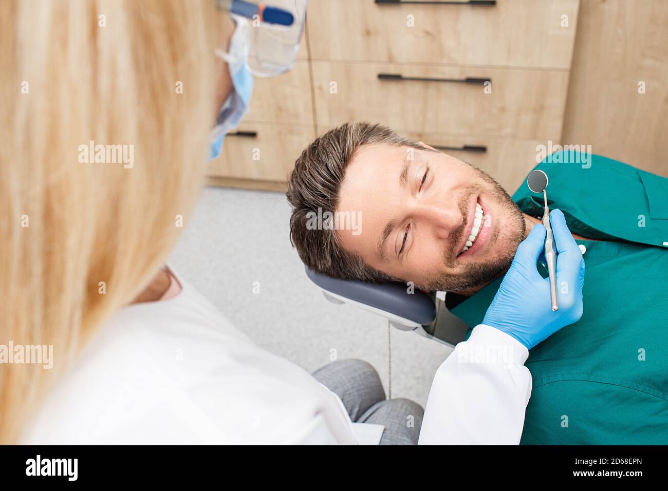 Bell'uomo sorridente mentre i denti esame. Paziente di sesso maschile felice seduto in una sedia del dentista e che ha controllare i denti Foto Stock