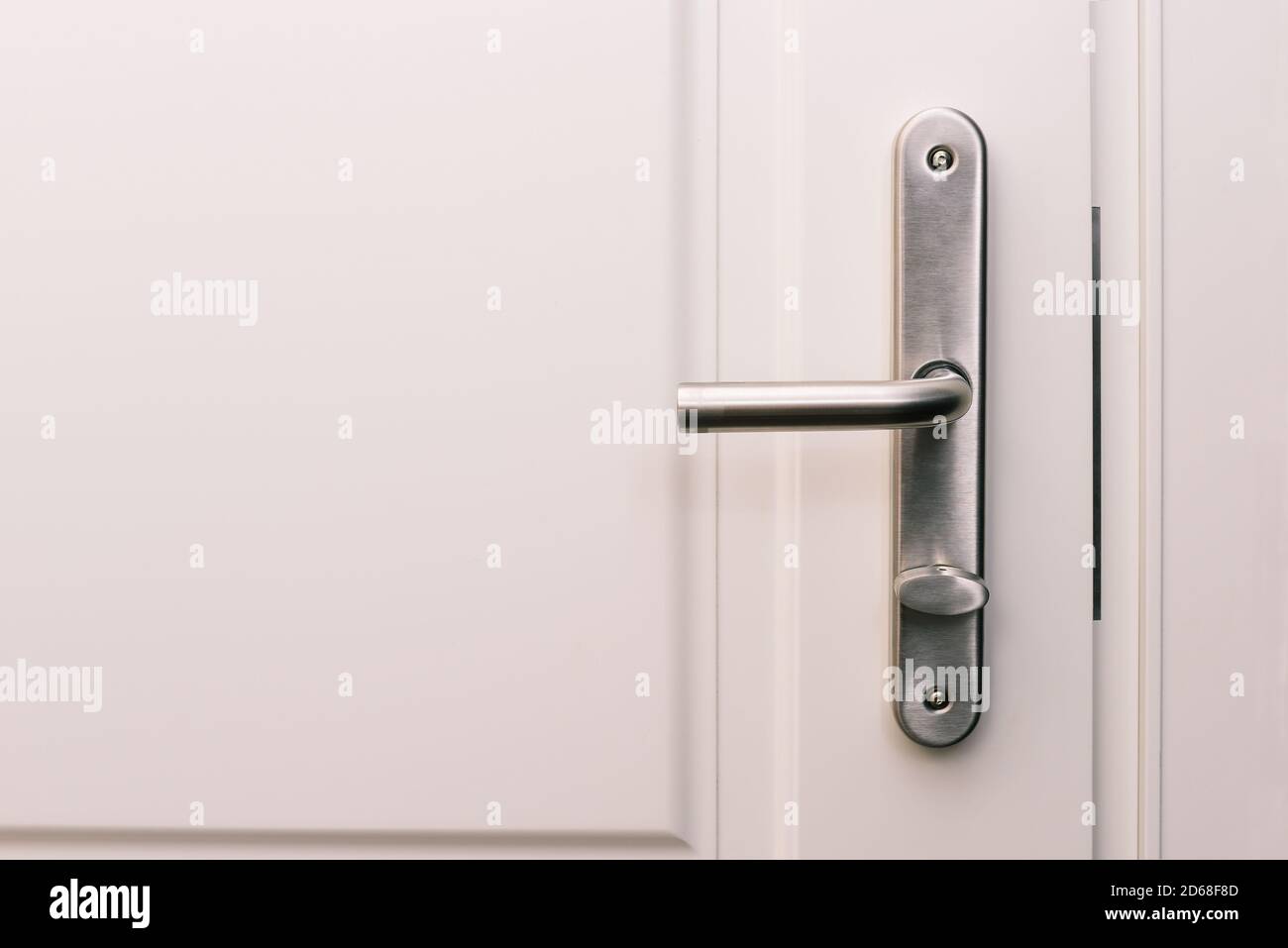 Sportello e maniglia bianchi. Ingresso ad un appartamento, un ufficio o una camera da letto. Dettaglio della porta. Interno di una casa o di un hotel. Foto Stock