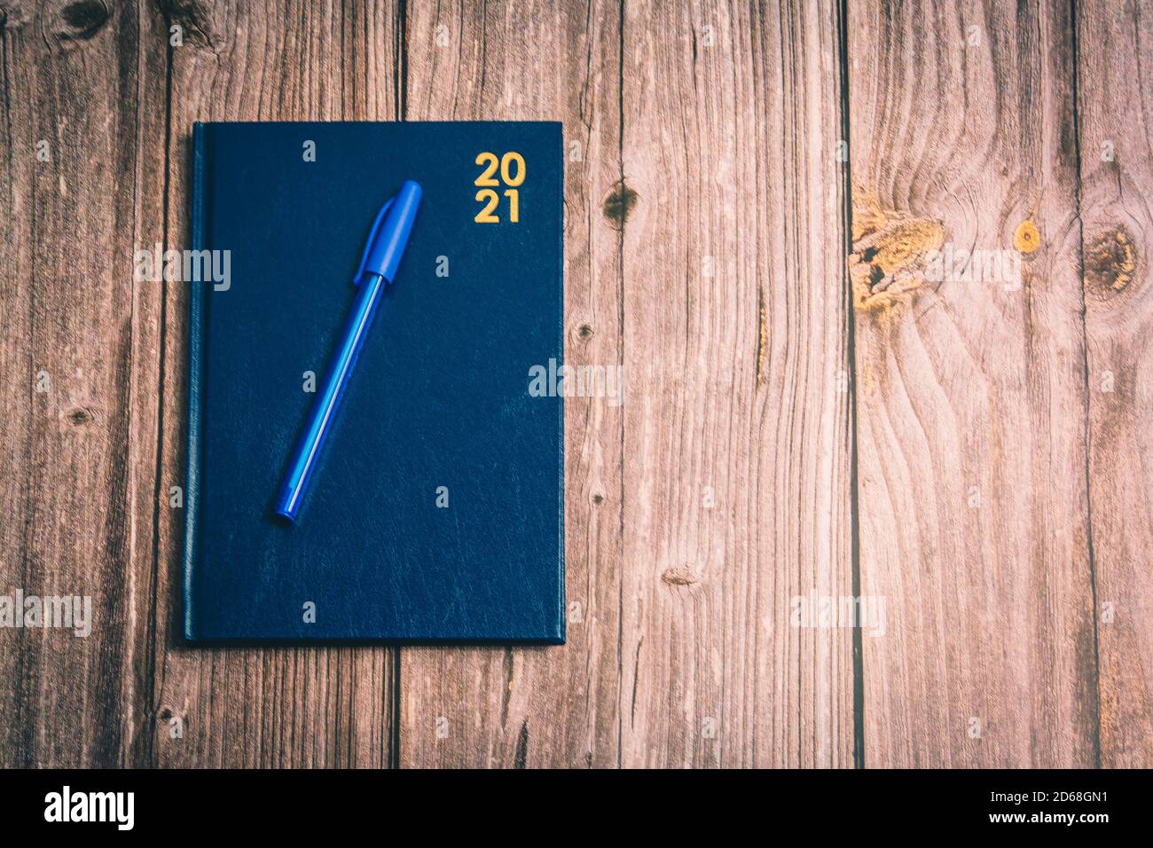 Una penna su un diario 2021 posto su un rustico scrivania in legno Foto Stock