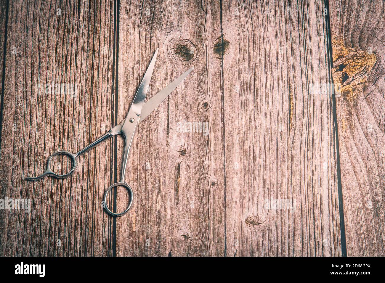 Un paio di forbici per capelli posate su un legno rustico tabella Foto Stock