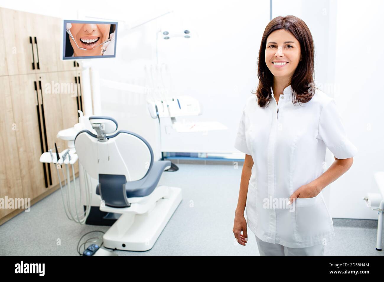Ritratto dentista femminile indossando occhiali protettivi, in piedi nella sua clinica. Foto Stock