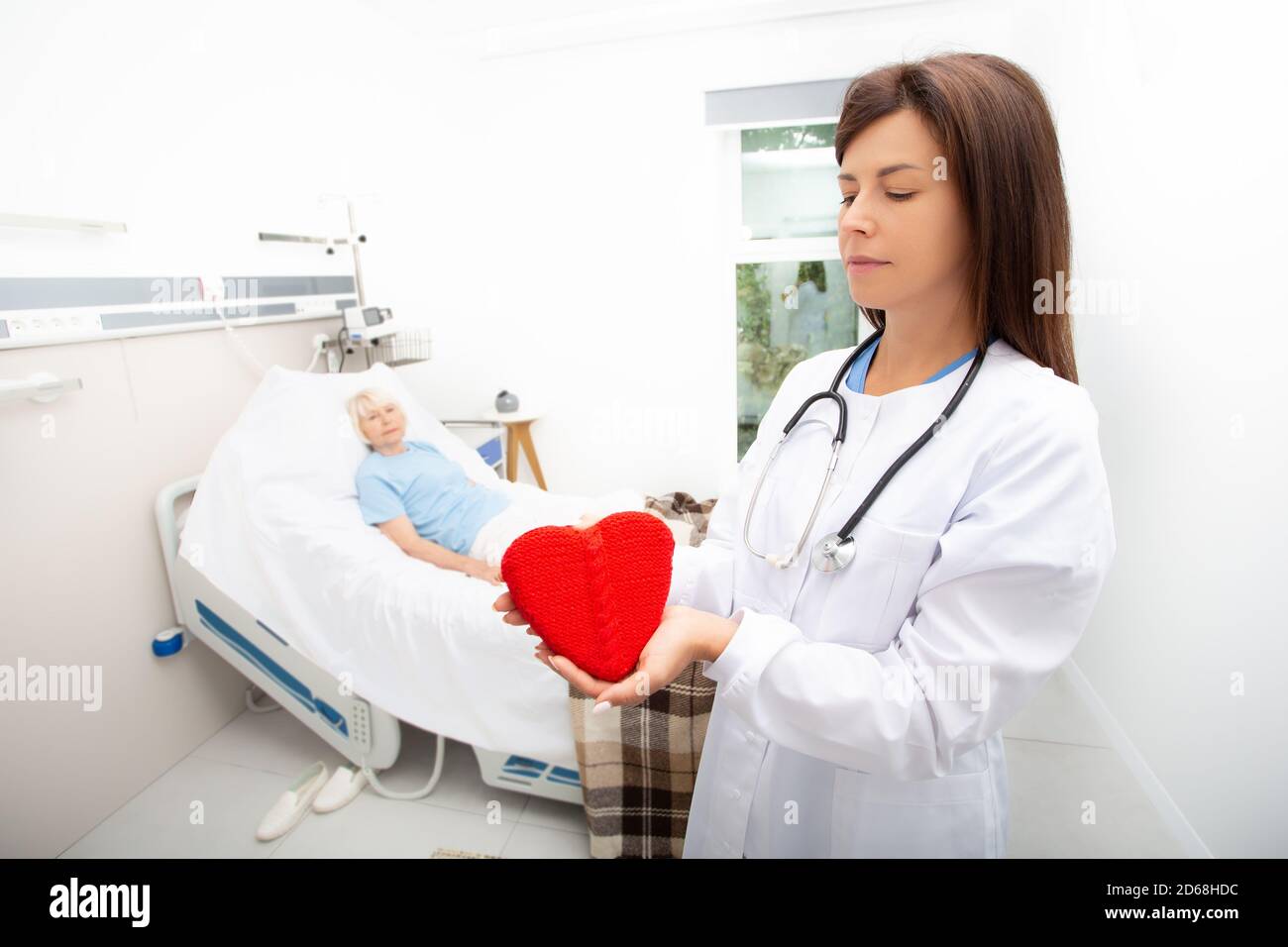Cura di un paziente anziano in ospedale. medico con un modello cardiaco. Cardiologia, assistenza medica per pazienti con malattie cardiache. Attacco di cuore, trattamento Foto Stock