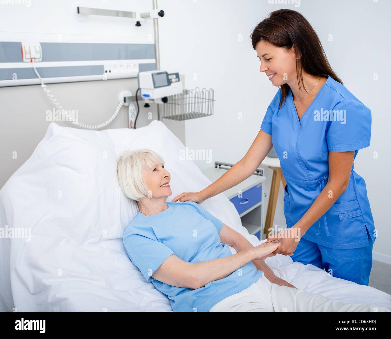 Infermiera cordiale che si prende cura di una donna anziana in una stanza dell'ospedale. Trattamento di pazienti anziani Foto Stock