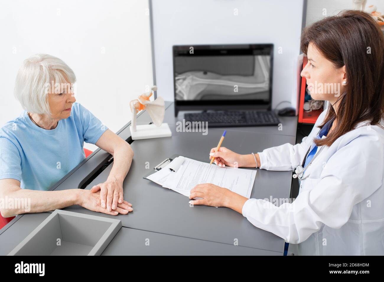 La donna anziana parla al medico osteopatico del dolore alle articolazioni e del tremore della mano. Diagnosi e trattamento dolore articolare nelle persone anziane Foto Stock