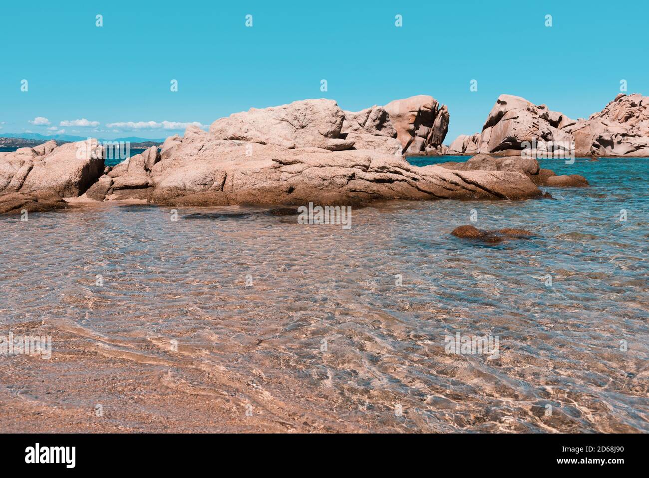 Una vista delle peculiari formazioni rocciose della costa della Baja Sardegna, in Sardegna, Italia, le acque cristalline del Mediterraneo in primo piano A. Foto Stock