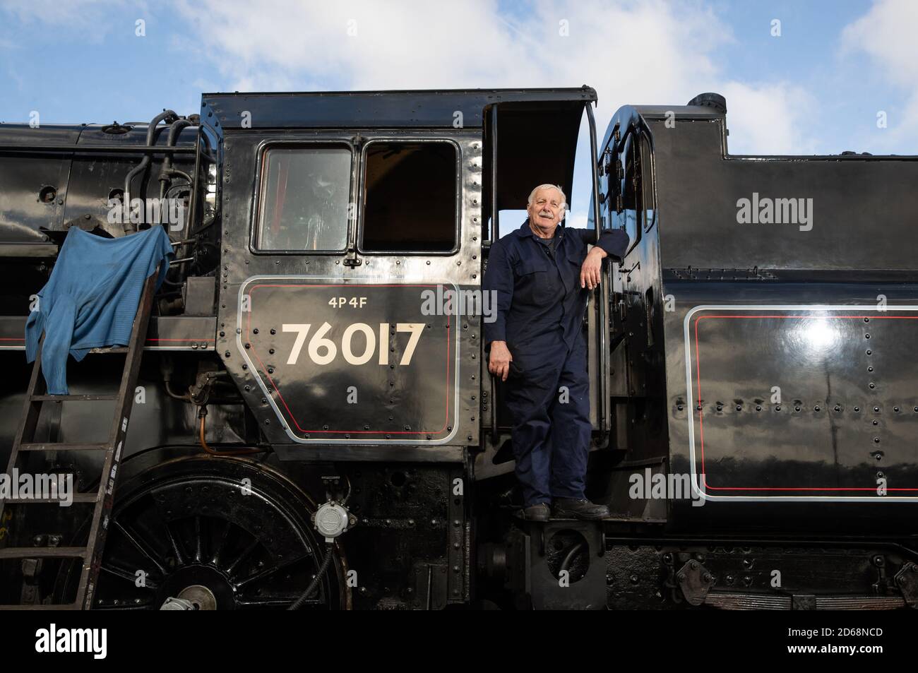 Driver Dave Pallett, Che si è offerto volontariamente sulla Mid Hants Railway per oltre 25 anni, guarda fuori dal taxi della British Railways Standard Class 4MT locomotiva a vapore 76017 come egli pone per una fotografia alla stazione di Rotley, in vista di questo weekend di autunno a vapore Gala sulla Mid Hants Railway's Watercress Line. Foto Stock