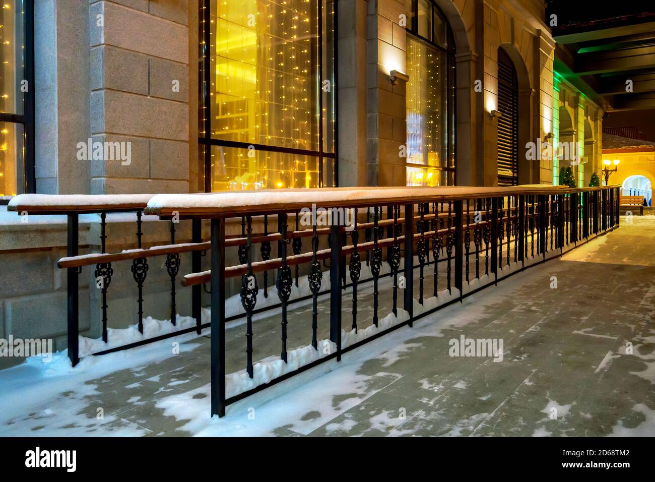 Rampa in metallo con corrimano in legno per carrozzine e carrozzine edificio in inverno sera Foto Stock