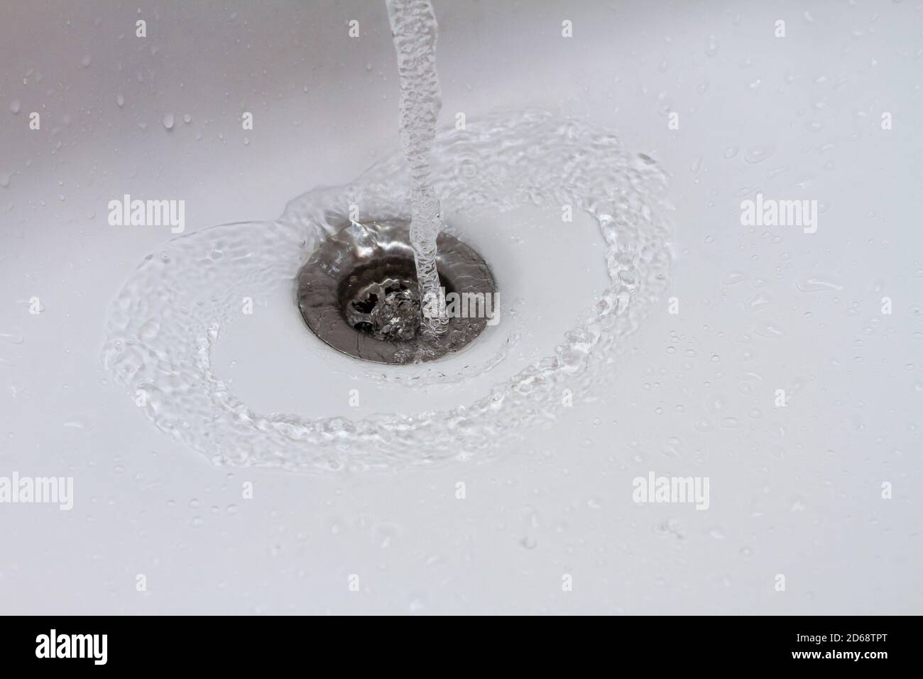 Acqua che scorre nella chiocciola di scarico del lavandino, goccia d'acqua che cade a lento movimento Foto Stock