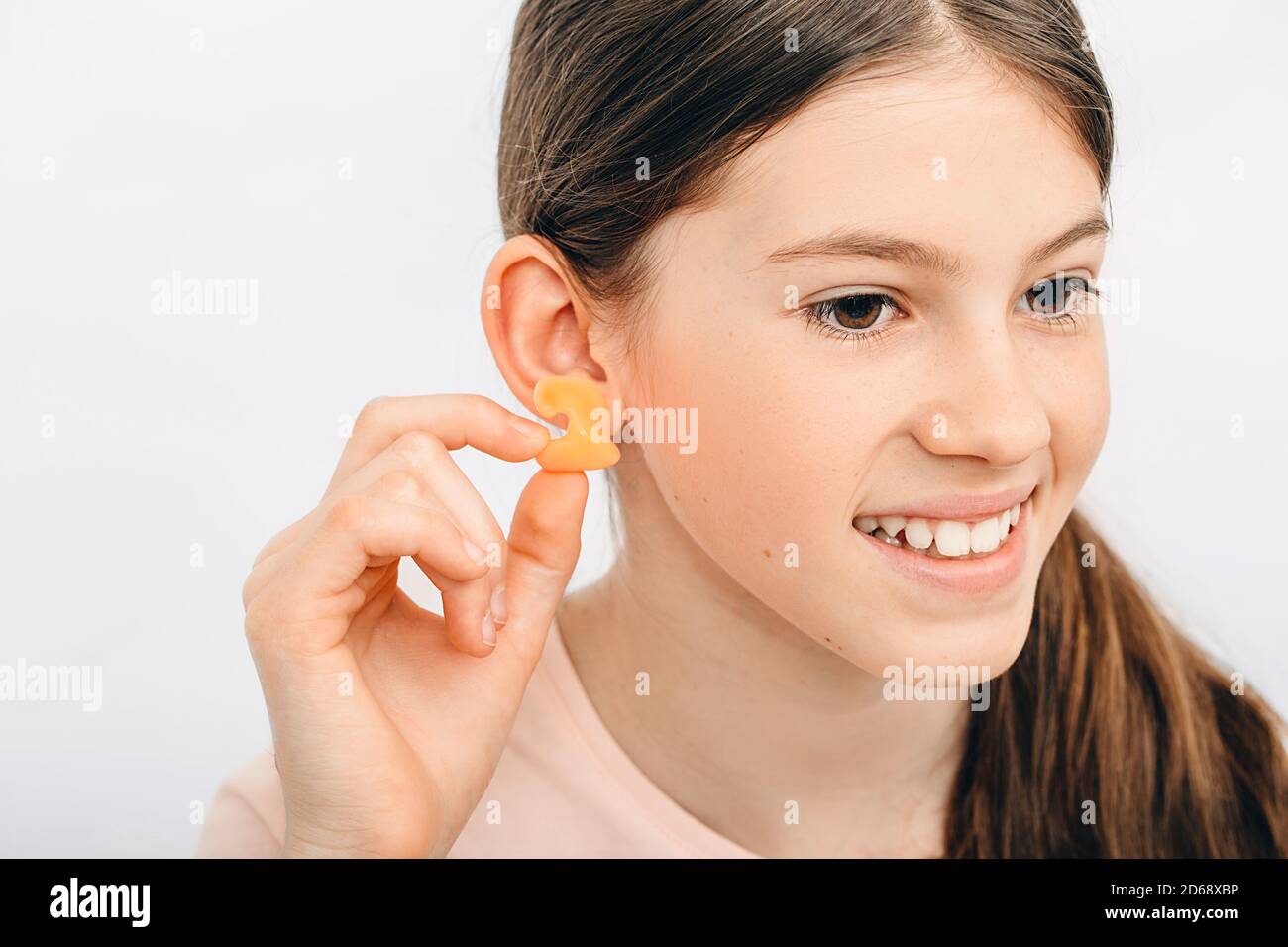 Tappi auricolari individuali per bambini. Ragazza che tiene il singolo auricolare vicino all'orecchio, primo piano. Foto Stock