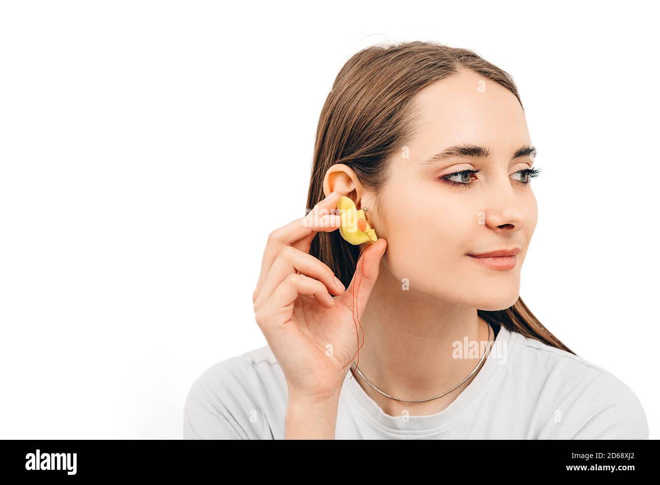 Tappi auricolari individuali per donne. Donna che tiene il tappo auricolare personalizzato vicino all'orecchio, su sfondo bianco Foto Stock