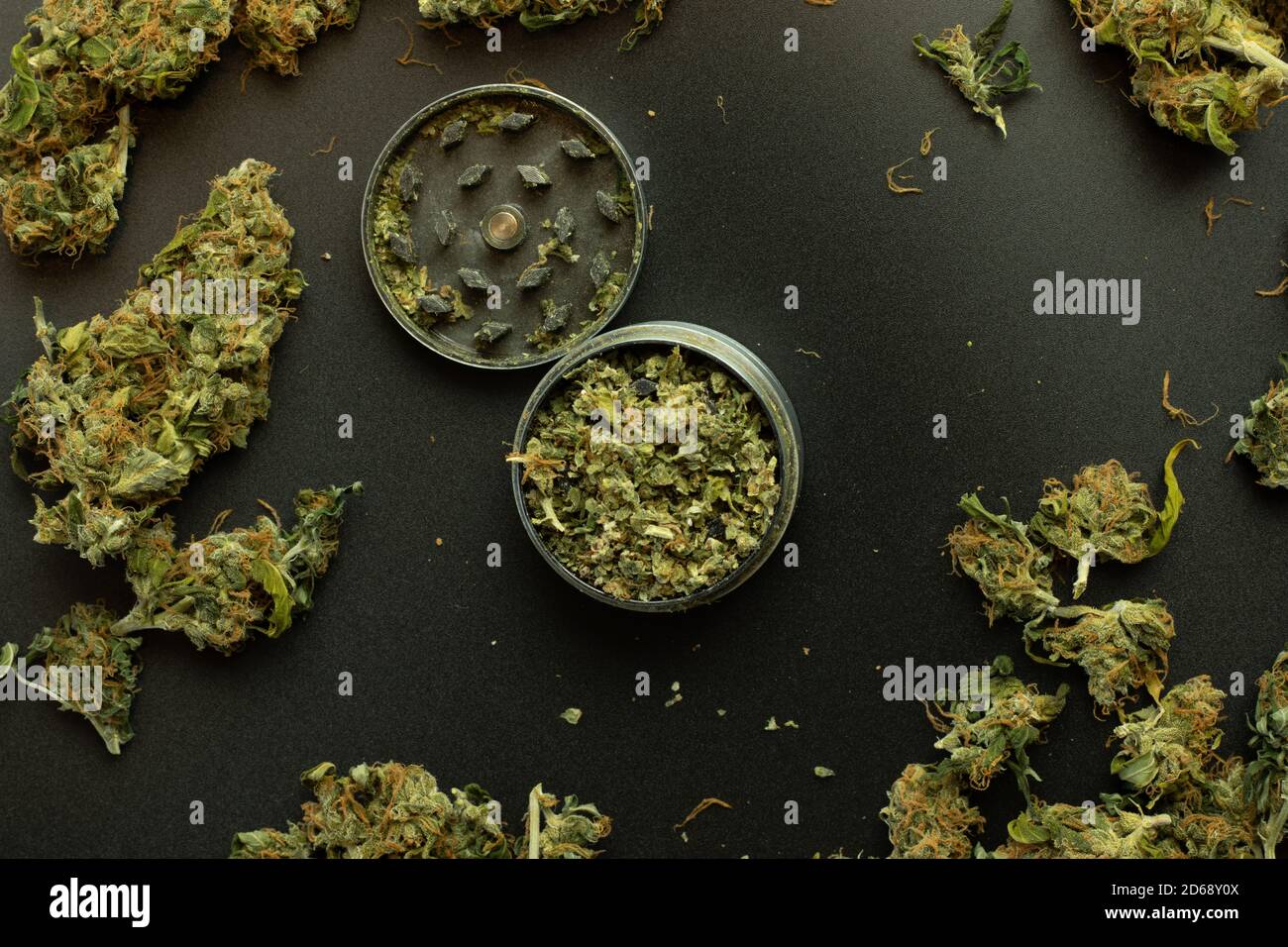 Piatto con cannabis, marijuana e erbacce. Vista dall'alto sul macinacaffè, sfondo nero. Illustrazione del THC Foto Stock