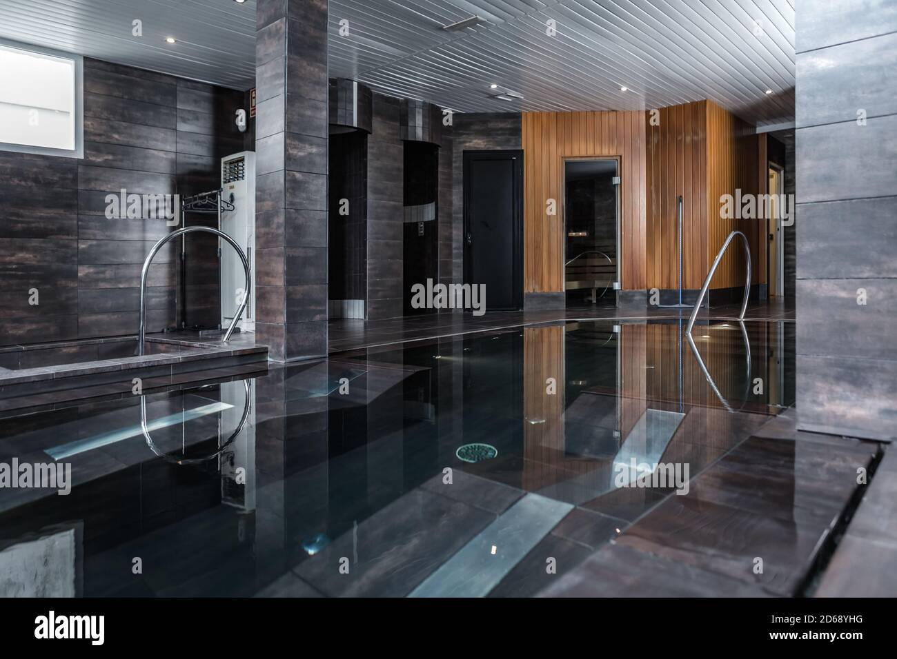 Interno di elegante camera con piscina di acqua pulita e. pareti piastrellate nel salone termale Foto Stock