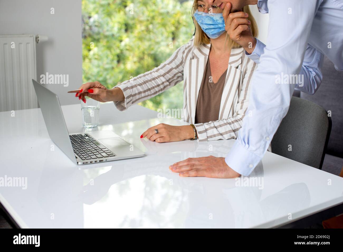 Uomini d'affari, donne e uomini con maschera aganista covid che parla di fronte al computer portatile in sala di lavoro. Coronavirus nel lavoro. Covid-19 in ufficio. Buissnes Foto Stock
